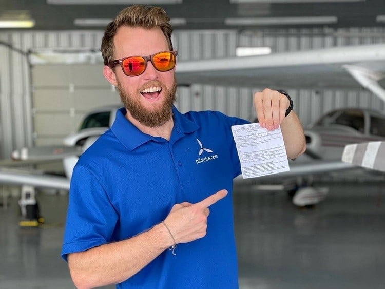Karl holding his new Commercial Pilot Certificate - Student Success